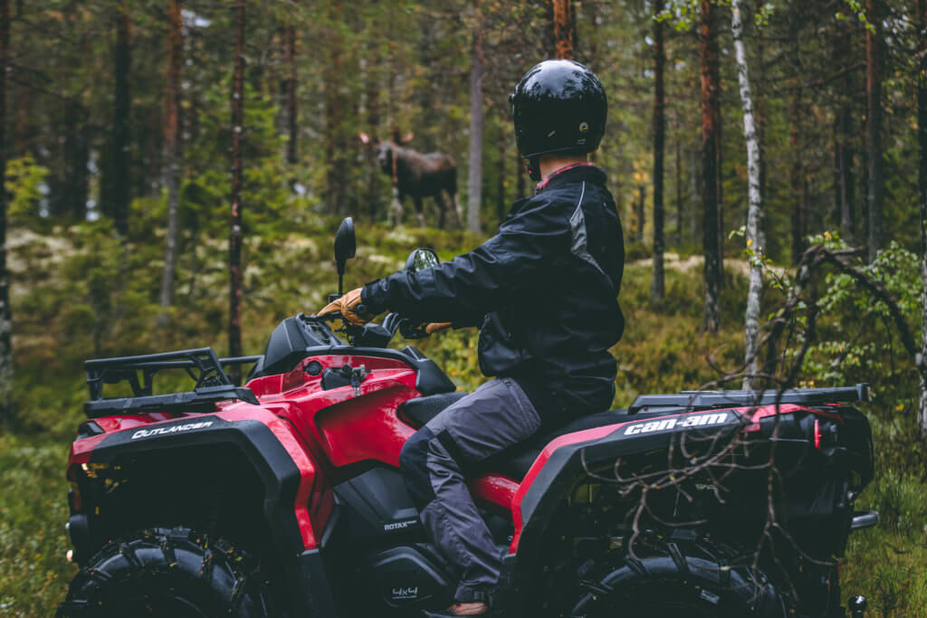 man riding atv in the forest looking at a moose