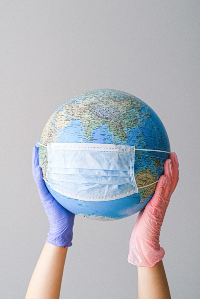 hand holding a globe with mask on