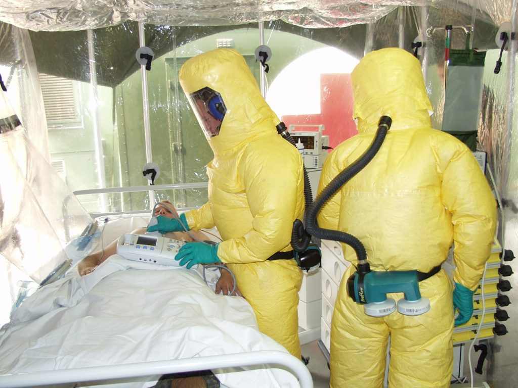 two doctors in PPE examining ebola infected patient in isolation