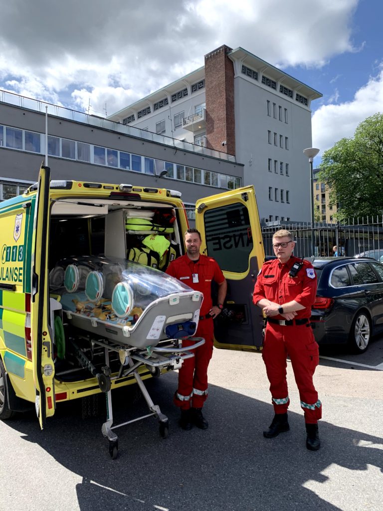 two paramedics in red loading the epishuttle onto ground ambulance
